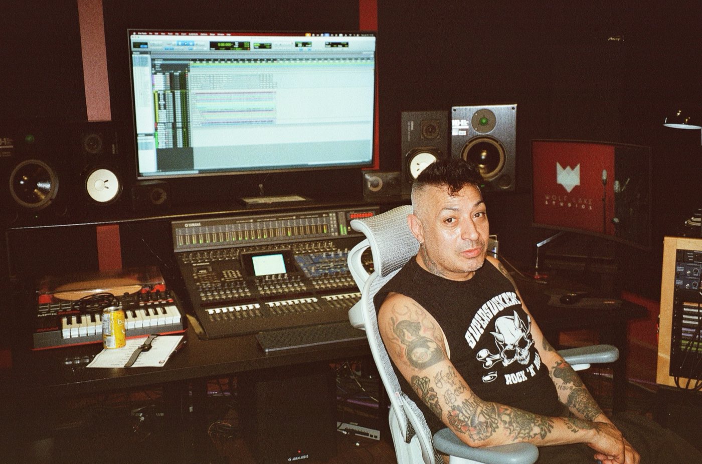 René De La Muerte at the mixing desk, the tracking room visible through the control-room glass behind him
